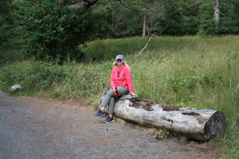 Cora Garvey sitting on a log outside near a trail